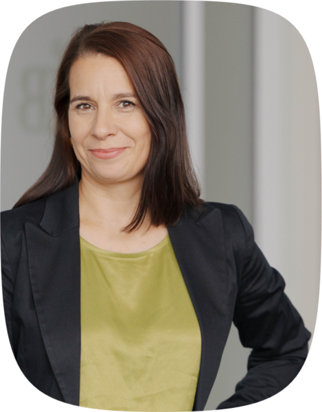 Porträt von Mieke Bethke: schulterlange braune Haare, trägt eine schwarze Jacke und ein olivgrünes Oberteil